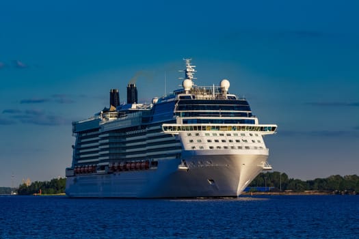 Giant white passenger ship moving past the port on a clear day