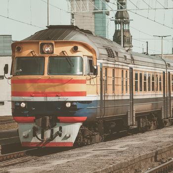 Old yellow passenger diesel train moving at the terminal