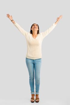 Studio shot of a happy young woman with arms raised