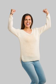 Studio shot of a happy young woman with arms raised