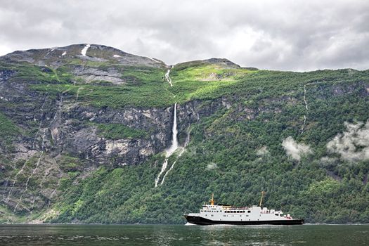 Cruise ship sailing in Geiranger in a cloudy day, Norway