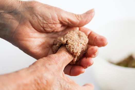 Step by step Levantine cuisine kibbeh preparation : Close up of a senior woman hands shaping a kibbeh