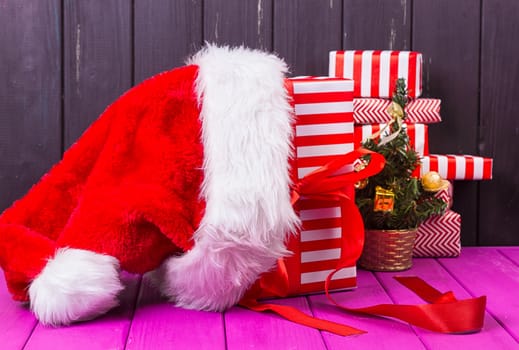 Gift boxes and small decorated Christmas tree and a Christmas cap on black background