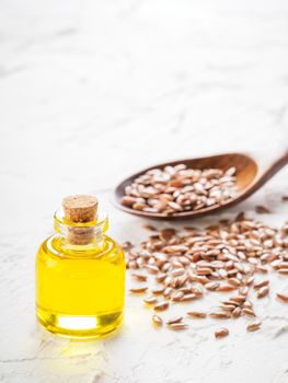 Brown flax seeds in spoon and flaxseed oil in glass bottle on white concrete background. Flax oil is rich in omega-3 fatty acid. Copy space.