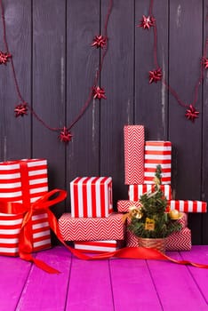 Gift boxes and small decorated Christmas tree on black background