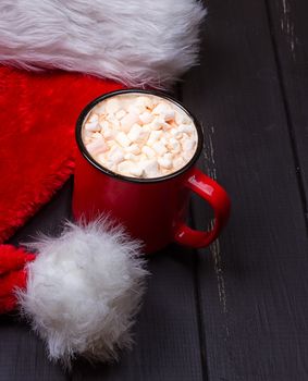 Hot chocolate with marshmallows and cap santa on grunge dark table