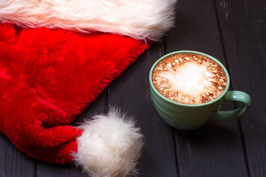 Hot chocolate with marshmallows and cap santa on grunge dark table