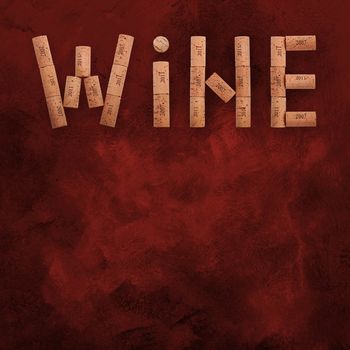 Word WINE shaped by natural wooden wine bottle corks of different vintage years over abstract grunge red paint background