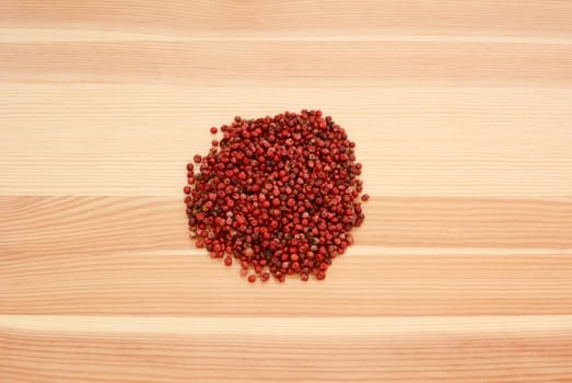 Pink peppercorns on a wooden background, pine wood grain