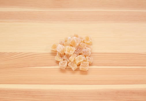 Cubes of crystallised stem ginger on a wooden background, pine wood grain