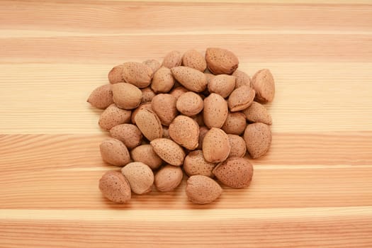 Almonds in shells on a wooden background, pine wood grain