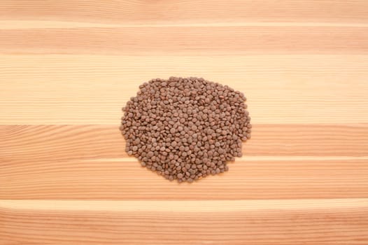 Brown lentils on a wooden background, pine wood grain