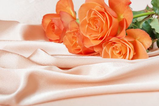 Bouquet of pink roses on satin fabric background