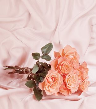 Bouquet of pink roses on satin fabric background with copy-space