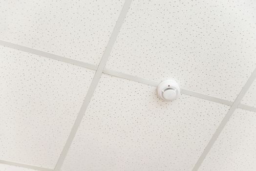 Smoke detector of fire alarm on the background of a white ceiling