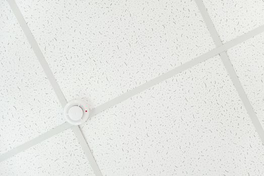 Smoke detector of fire alarm on the background of a white ceiling