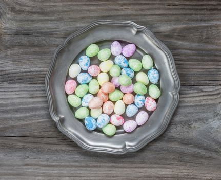 Many multi-colored Easter eggs in an ancient tin plate on an old wooden table