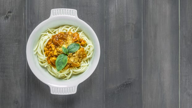 Plate of delicious spaghetti bolognese with savory minced beef and tomato sauce garnished with  basil, overhead view