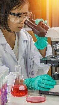 asian little girl looking with microscope in laboratory