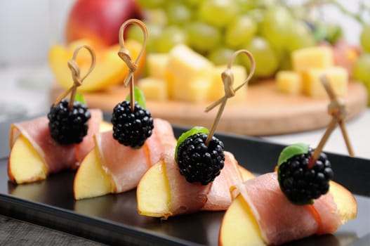 Canape from peach with dried ham and blackberries