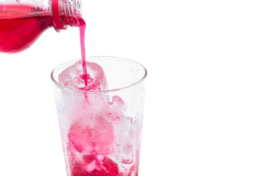 Closeup pouring  red soft drink with strawberry flavor into the glass on white background