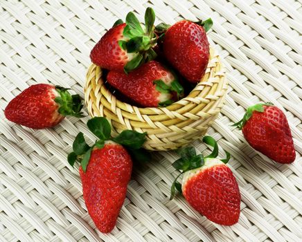 Arrangement of Big Ripe Strawberries in Wicker Bowl closeup on White Wicker background