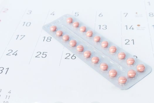 Close up birth-control pill with date of calendar background, health care and medicine concept