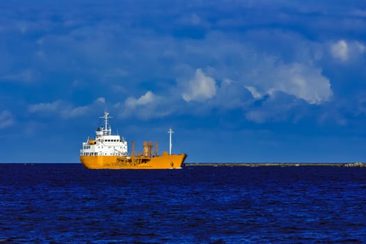 Yellow cargo tanker ship moving at the clear summer day