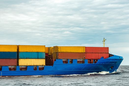 Blue cargo container ship fully loaded underway