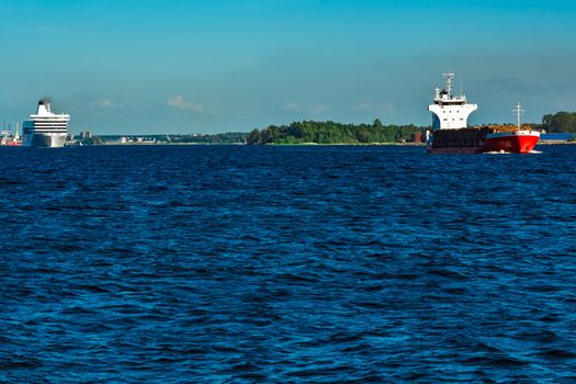 Red cargo ship fully loaded with wood moving at clear day
