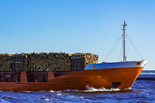 Orange bulk carrier sailing in clear summer day