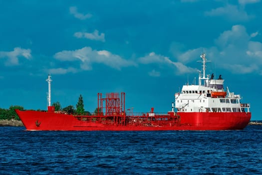 Red cargo tanker ship moving by the river