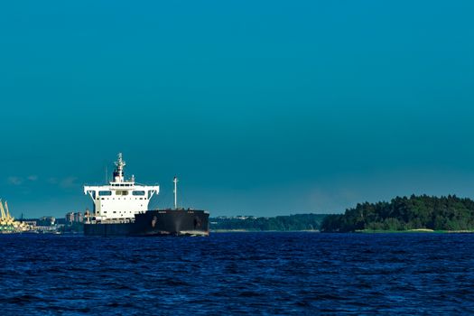 Black cargo ship moving to Baltic sea at clear day