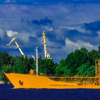 Yellow cargo tanker ship moving at the clear summer day