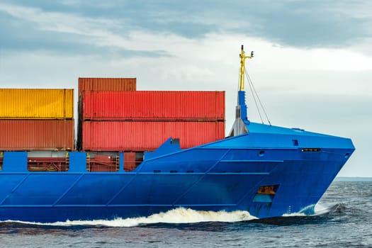Blue cargo container ship fully loaded underway