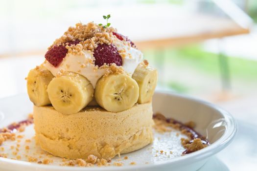 Hot cake with cream, strawberry, banana and cookie crumble on white dish