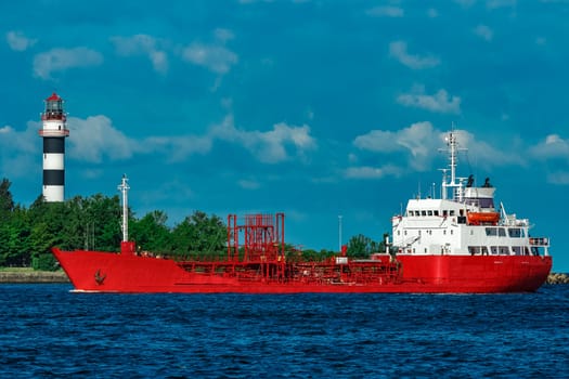 Red cargo tanker ship moving by the river