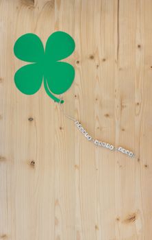 The german words for Happy New Year and a cloverleaf on a cord on wood