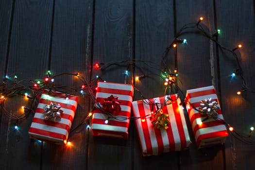 Gift box and garland lights over old wooden background