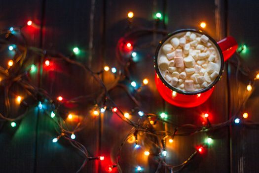 Decorative garland. Christmas lights on dark background and cup.