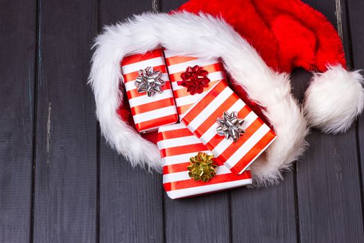 Christmas gifts in a Santa Claus hat on a black wooden background