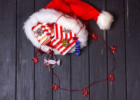 Christmas gifts in a Santa Claus hat on a black wooden background