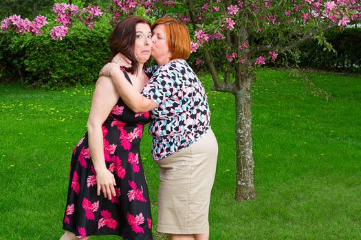 woman surprising a kiss on a cheek of a friend