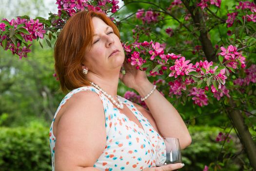 middle aged woman enjoying the flower from a cherry tree