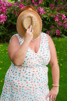 woman hidding behind a straw hat and flipping the bird
