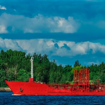 Red cargo tanker ship moving by the river