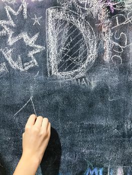 Back to school. A child paints scribbles by chalk on a board