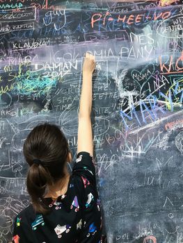 Back to school. A child paints scribbles by chalk on a board