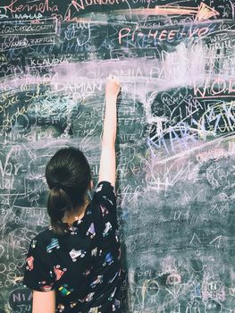 Back to school. A child paints scribbles by chalk on a board