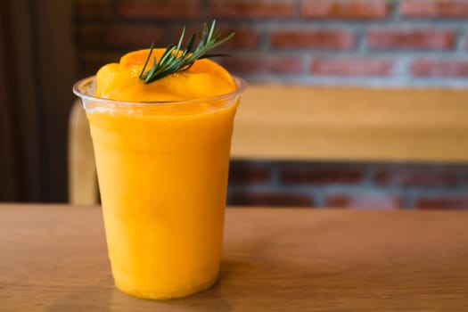 Fresh mandarin smoothie in glass on wooden table